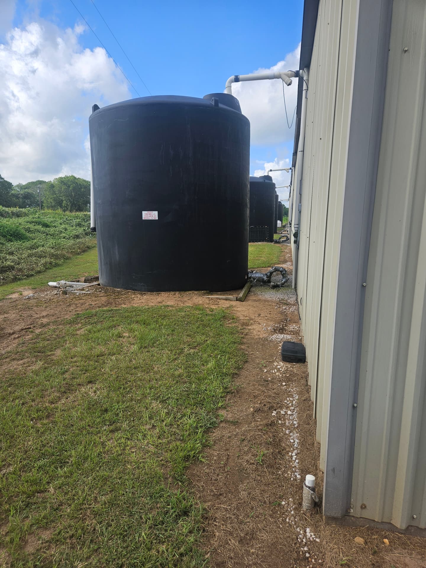 Rainwater harvesting storage tanks connected to a building in a real-world water infrastructure setting.